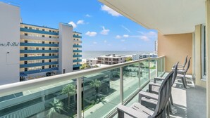 Un balcone con ringhiera in vetro che si affaccia su una città e il mare.