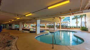 Una piscina interna con un cartello che indica acqua bassa e divieto di tuffi.