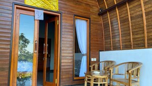 A wooden room with a sliding glass door, a small table, and two wooden chairs. - Kubuhill Sunset Bungalow (Penida Island)
