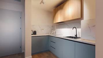 A modern kitchen with light blue cabinets, a marble backsplash, and a black faucet.