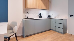Une cuisine moderne avec des meubles de couleur grise, un meuble supérieur en bois, un plan de travail en marbre et un robinet noir.