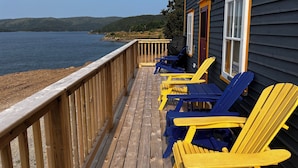 A wooden deck with yellow and blue Adirondack chairs facing a lake. - Bellecroft House - Beautifully renovated, stunning water-front getaway property (Trinity East)