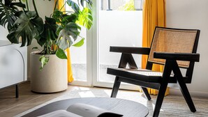 A room with a large potted plant, a chair, and a table with a book. - Mate Levinski - By HOMY (Tel Aviv)