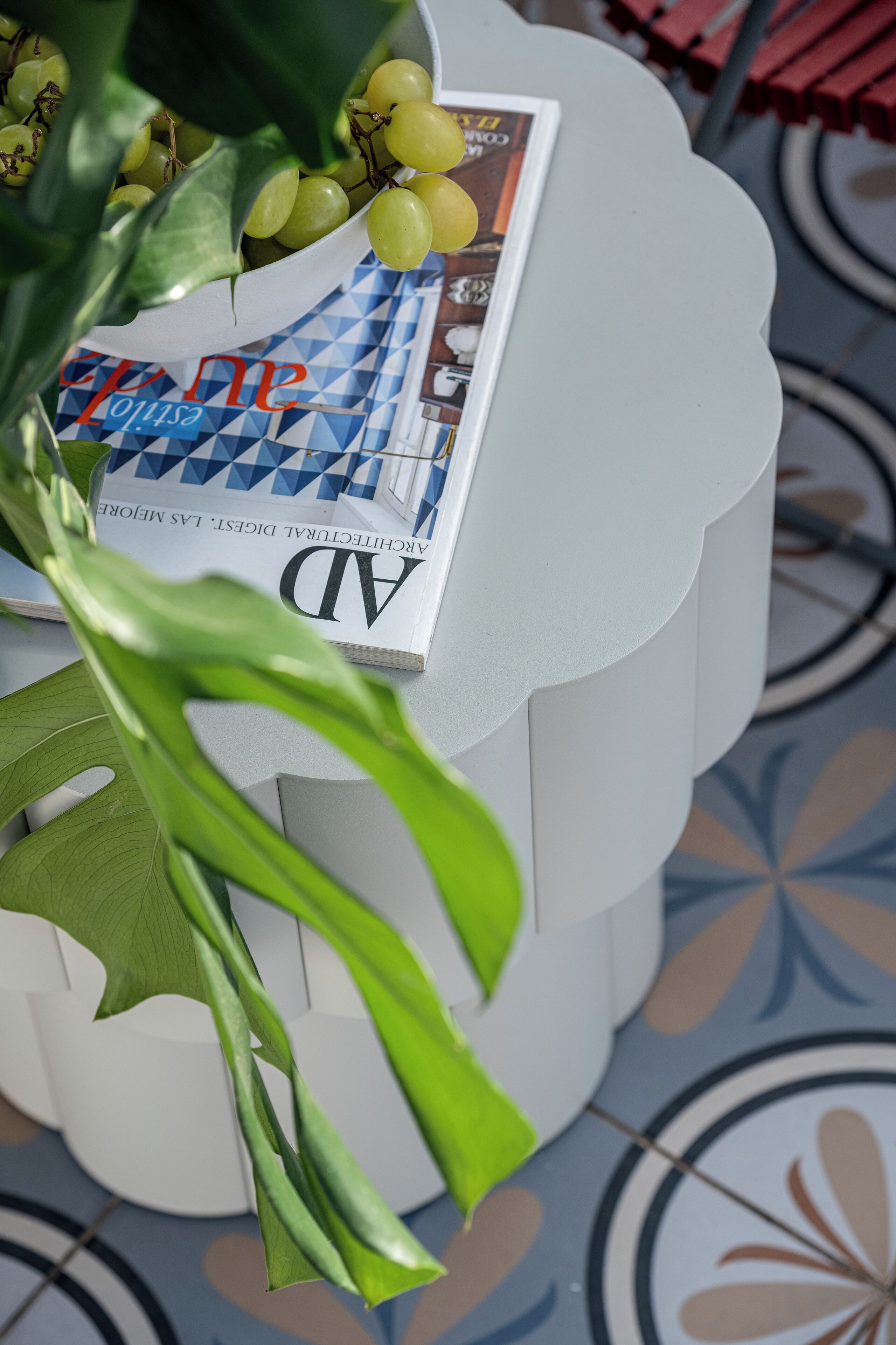 Un présentoir blanc à plusieurs niveaux, surmonté d’un magazine et de feuilles vertes.