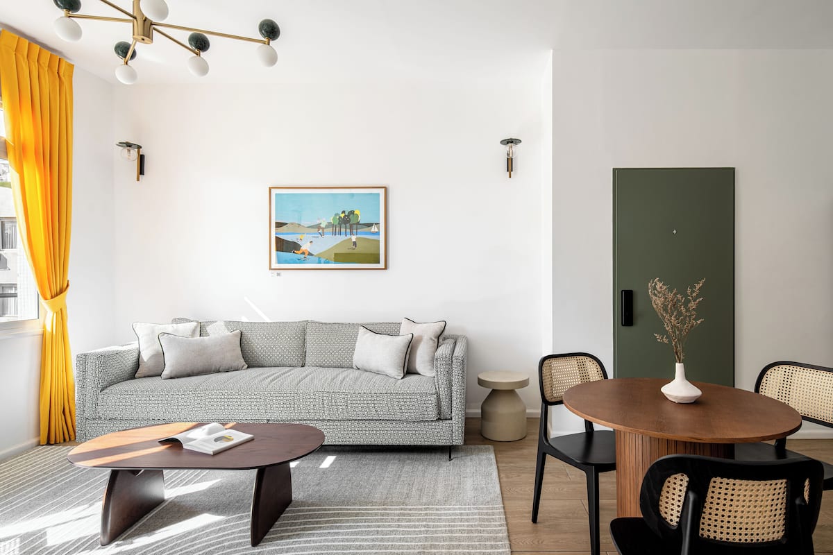 A modern living room with a sofa, coffee table, and dining area.