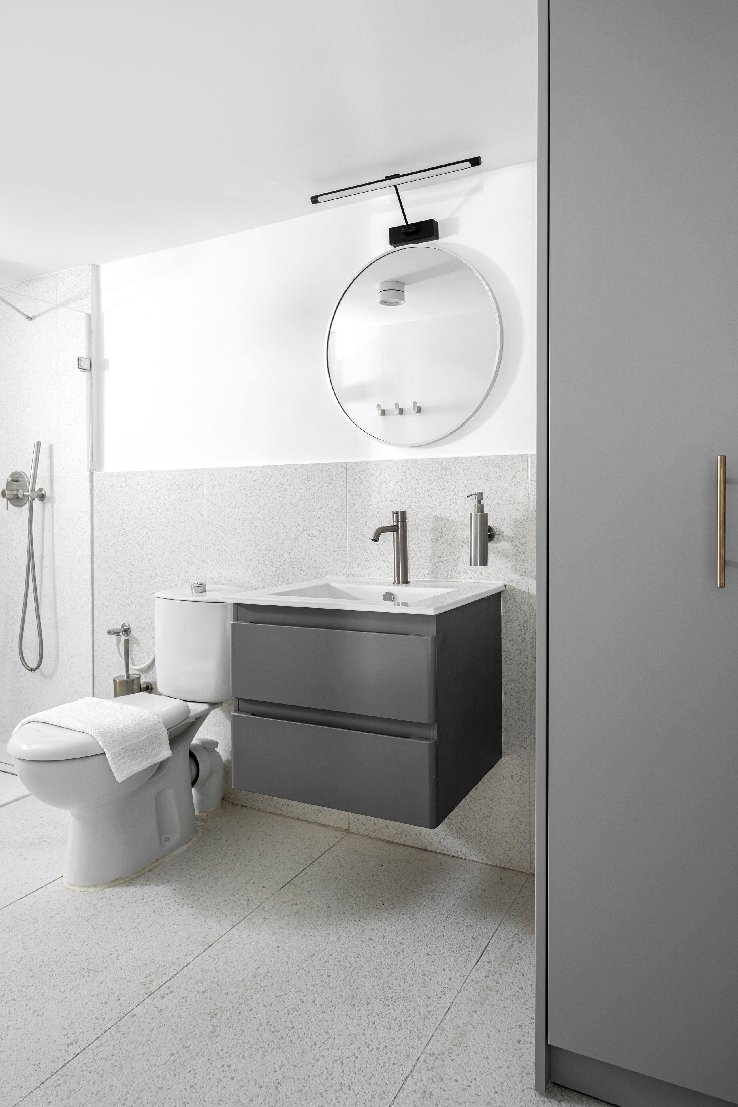 Une salle de bain moderne avec un lavabo blanc, un miroir rond et des toilettes.