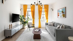 A modern living room with a sofa, a coffee table, a TV, and a potted plant. - Mate Levinski - By HOMY (Tel Aviv)