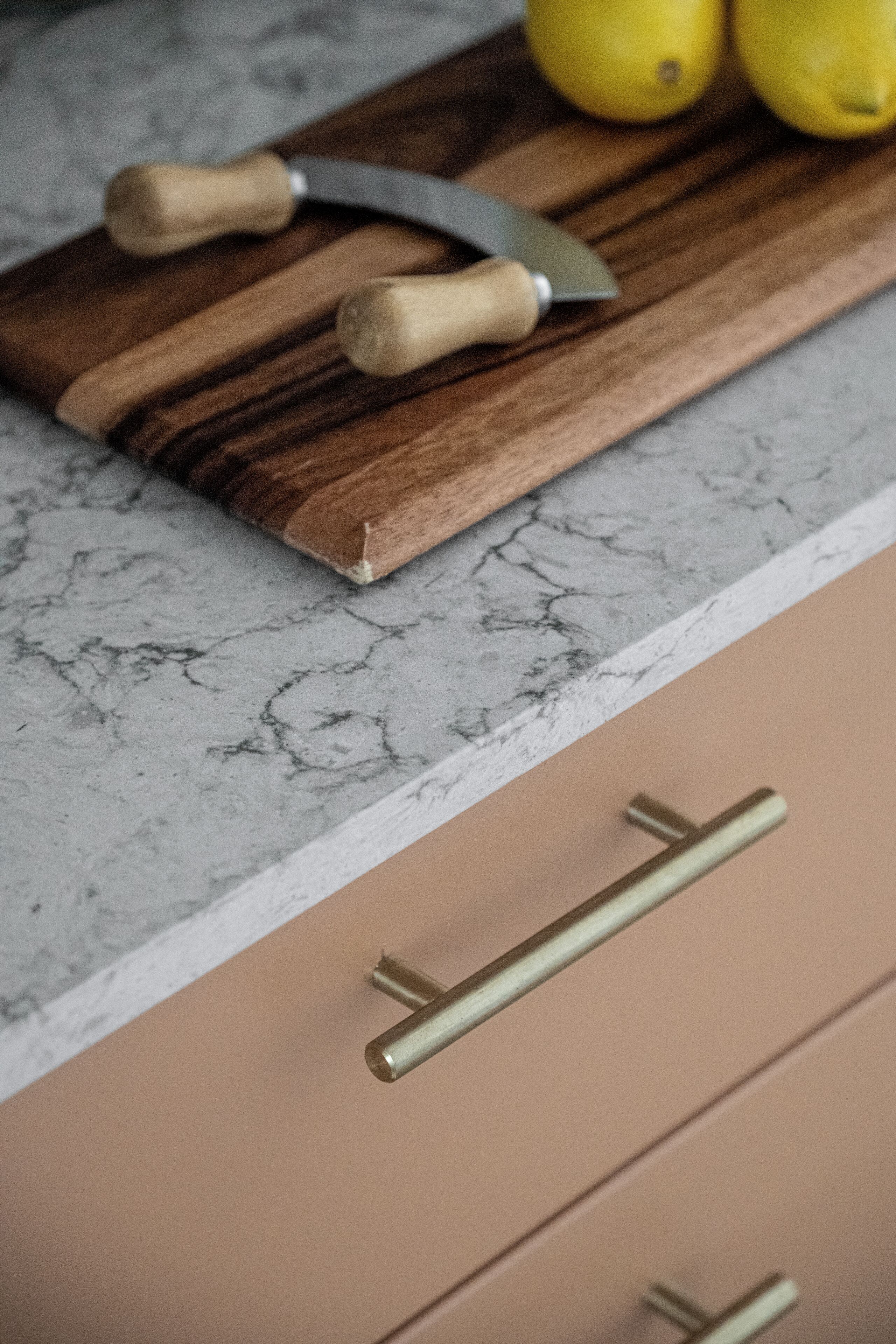 A kitchen counter with a cutting board, two lemons, and a knife.