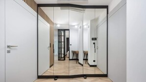 A modern room with a mirrored wardrobe, a wooden slatted wall, and a herringbone-patterned floor.