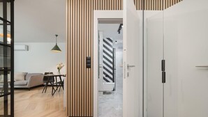 A modern interior with a wooden panel wall, a dining area with a table and chairs, a sofa, and a white wardrobe.