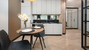 A modern kitchen with white cabinets, a black countertop, and a dining area with a round table and chairs.