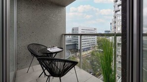 A balcony with a table and chairs, a view of a cityscape, and a building in the background.