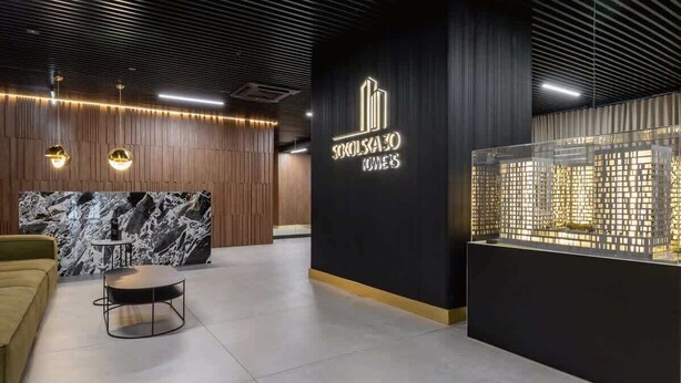 A modern reception area with a marble counter, a sofa, and a display case.