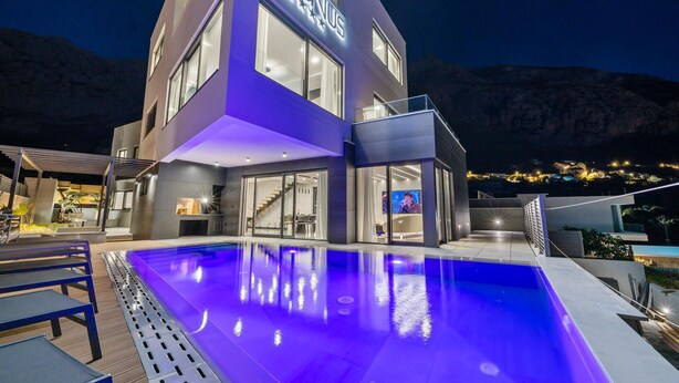 Un hotel moderno con piscina, ventanas amplias y vistas a la montaña.