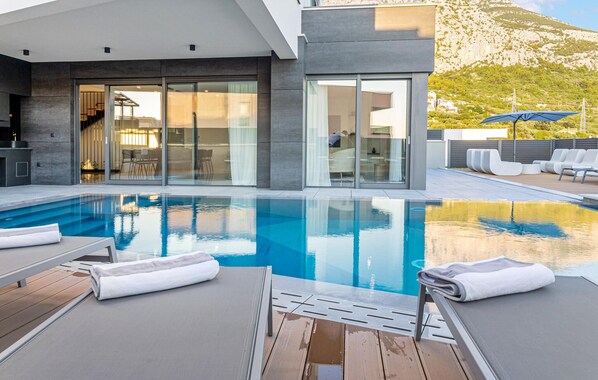 A modern outdoor pool area with lounge chairs and a clear view of the surrounding landscape.