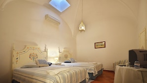 A room with two beds, a ceiling fan, a table with a computer and a bottle, and a small window. - Casa de Serpa - turismo rural (Serpa)