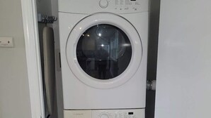 A compact, white front-loading washer and dryer unit with a control panel on the top and a front door.