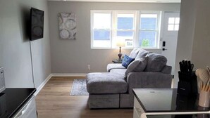 A compact living space with a kitchenette, a sofa, and a window with a view.