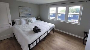 A bedroom with a bed, a window, and a door. - Midtown Retreat Near Dundee & UNMC (Omaha)