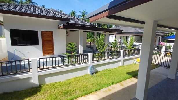 A residential building with a covered porch, a wooden door, and a small garden area.