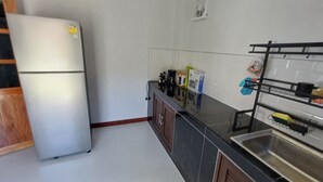 A kitchen with a refrigerator, cabinets, a countertop with appliances, and a sink.