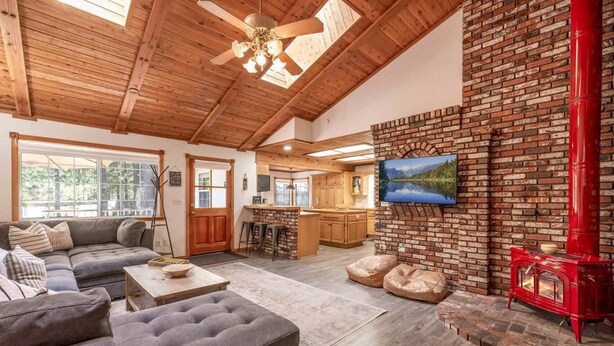 A cozy living room with a fireplace, a kitchen area, and a dining space. - Summer Retreat|5BR Stay Near Lake, Hikes~Water Fun (Big Bear Lake)