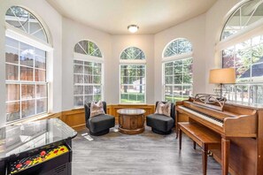 A room with a piano, two armchairs, a small table, and a jukebox.