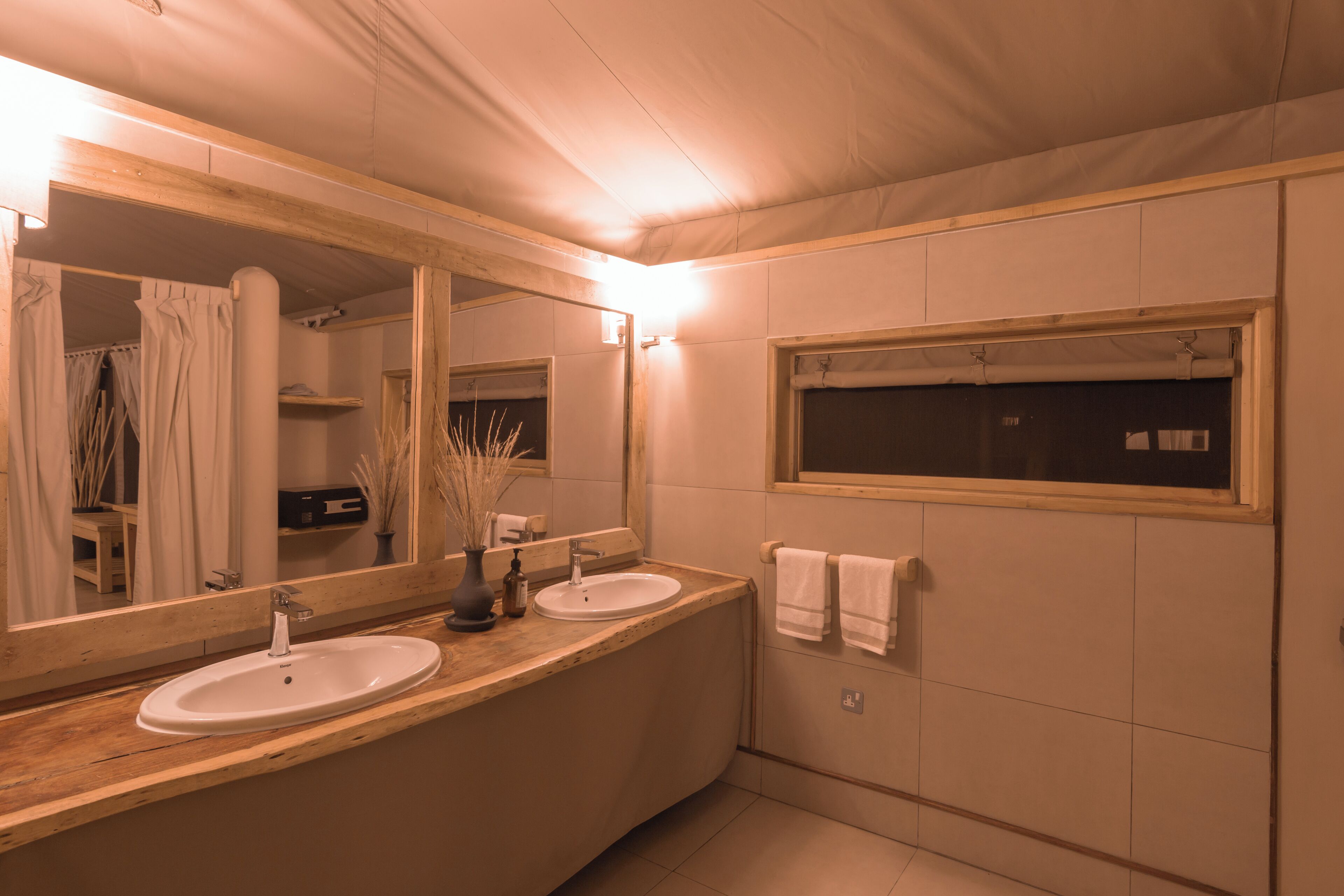 A modern bathroom with two sinks, a large mirror, and a window.