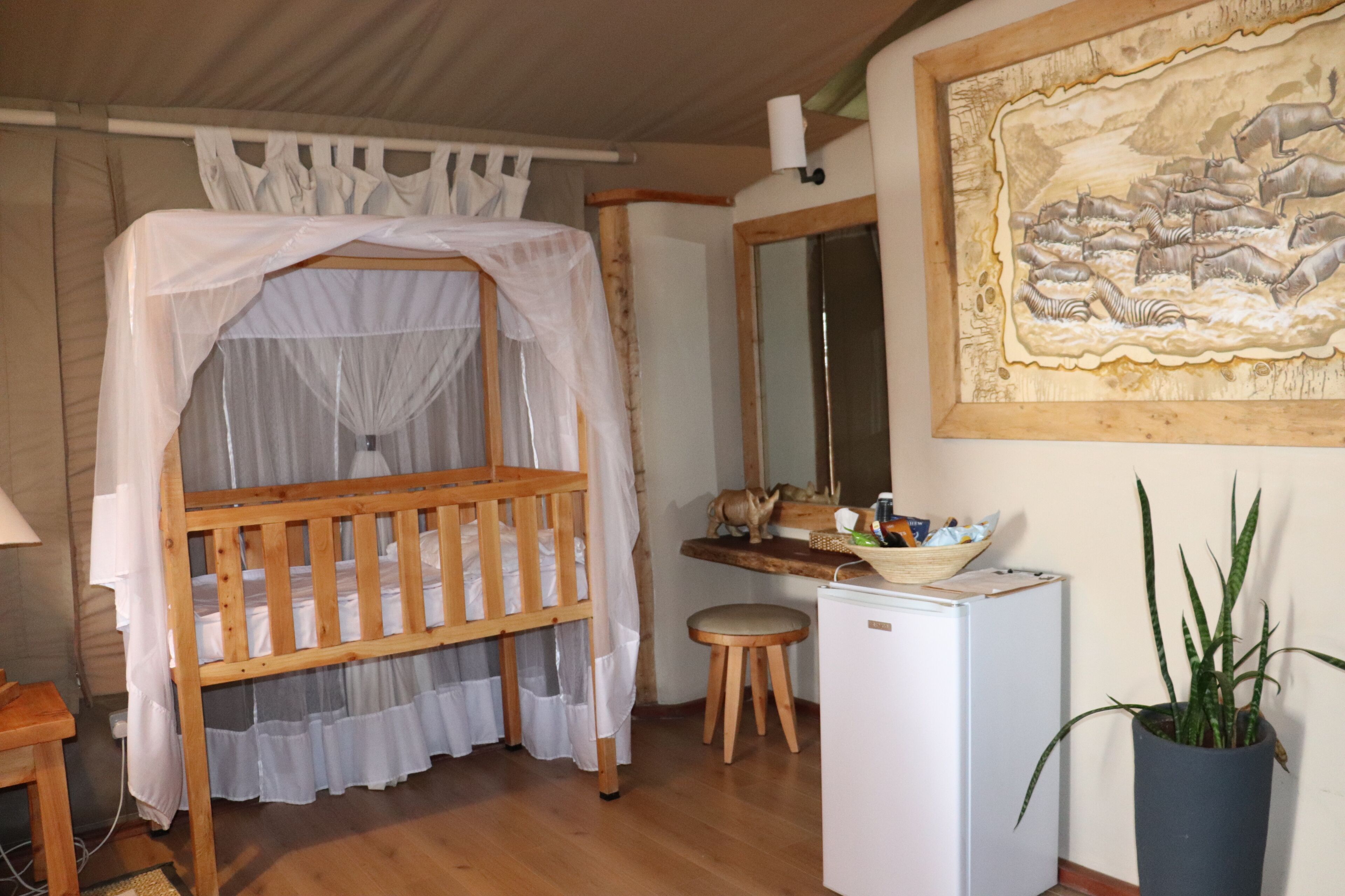 A room with a wooden bunk bed, a small stool, a white refrigerator, and a potted plant.