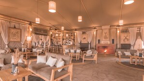 Un amplio salón con sofás, mesas y chimenea.