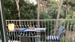Un balcon avec une table dressée pour deux personnes, des chaises et une lampe.