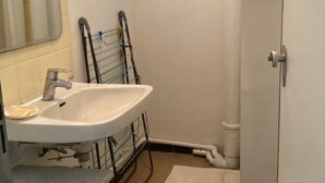 Une petite salle de bain avec un lavabo, un miroir, une serviette et une fenêtre.