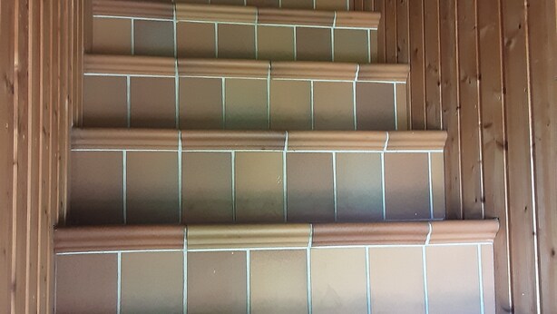 Eine Treppe mit braunen Fliesen und Holzgeländern.