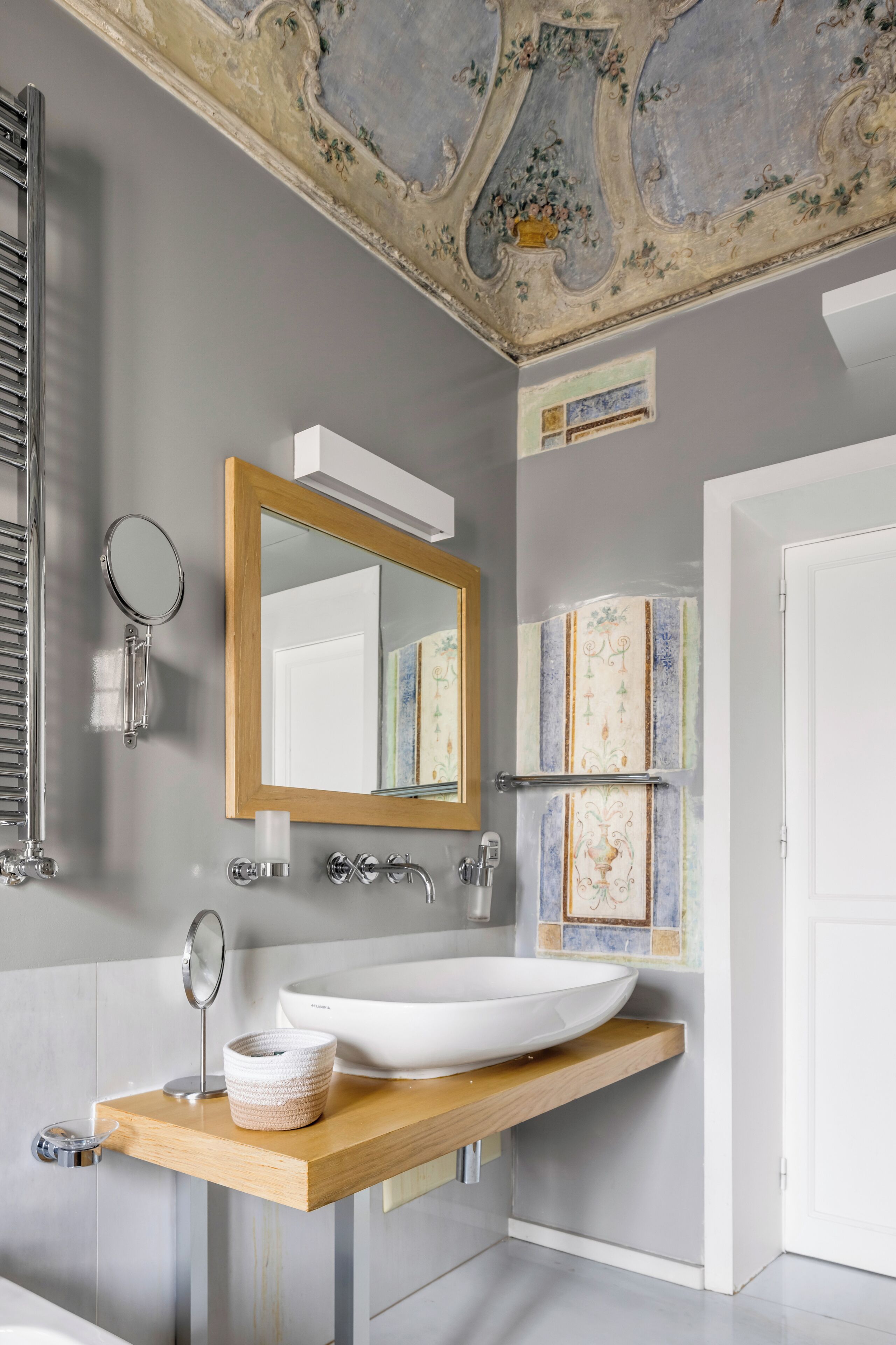A bathroom with a large white sink, a wooden countertop, a mirror, and a decorative ceiling.