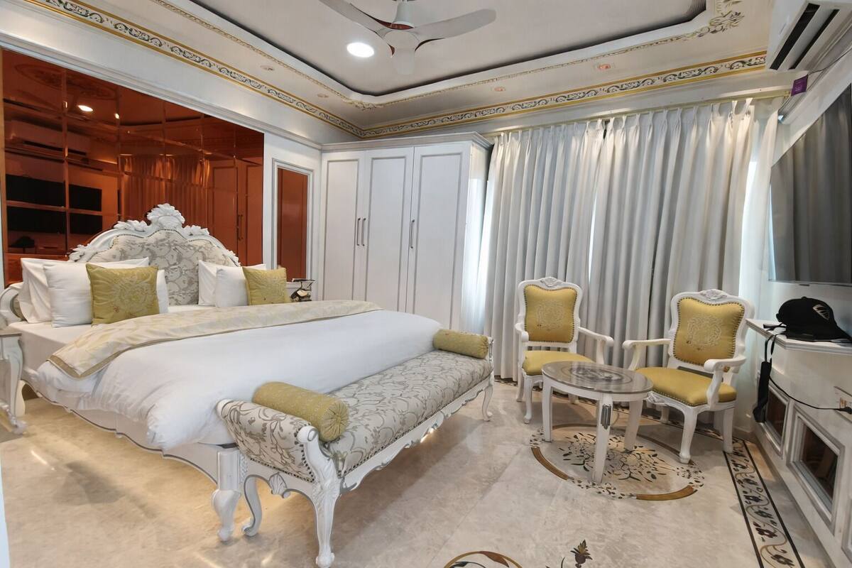 A spacious bedroom with a large bed, two chairs, a small table, and a TV.