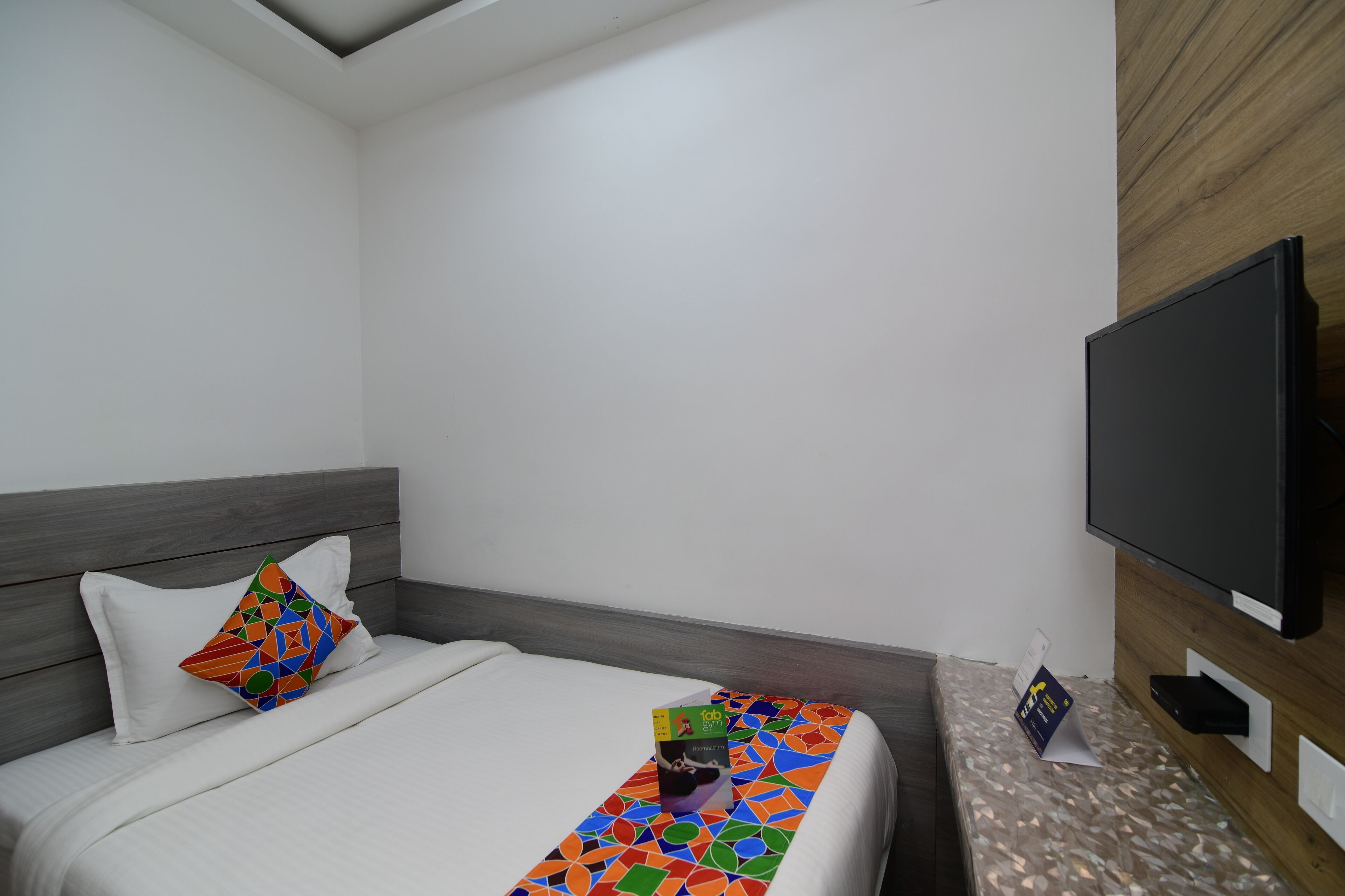 A hotel room with a bed, a TV, and a wooden wall.