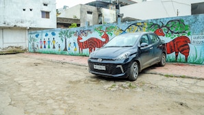 A car parked in front of a building with a colorful mural on the wall. - Hotel Dev Krishna Palace (Ujjain)