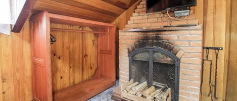 Una habitación acogedora con chimenea, paredes de madera y televisor montado en la pared.