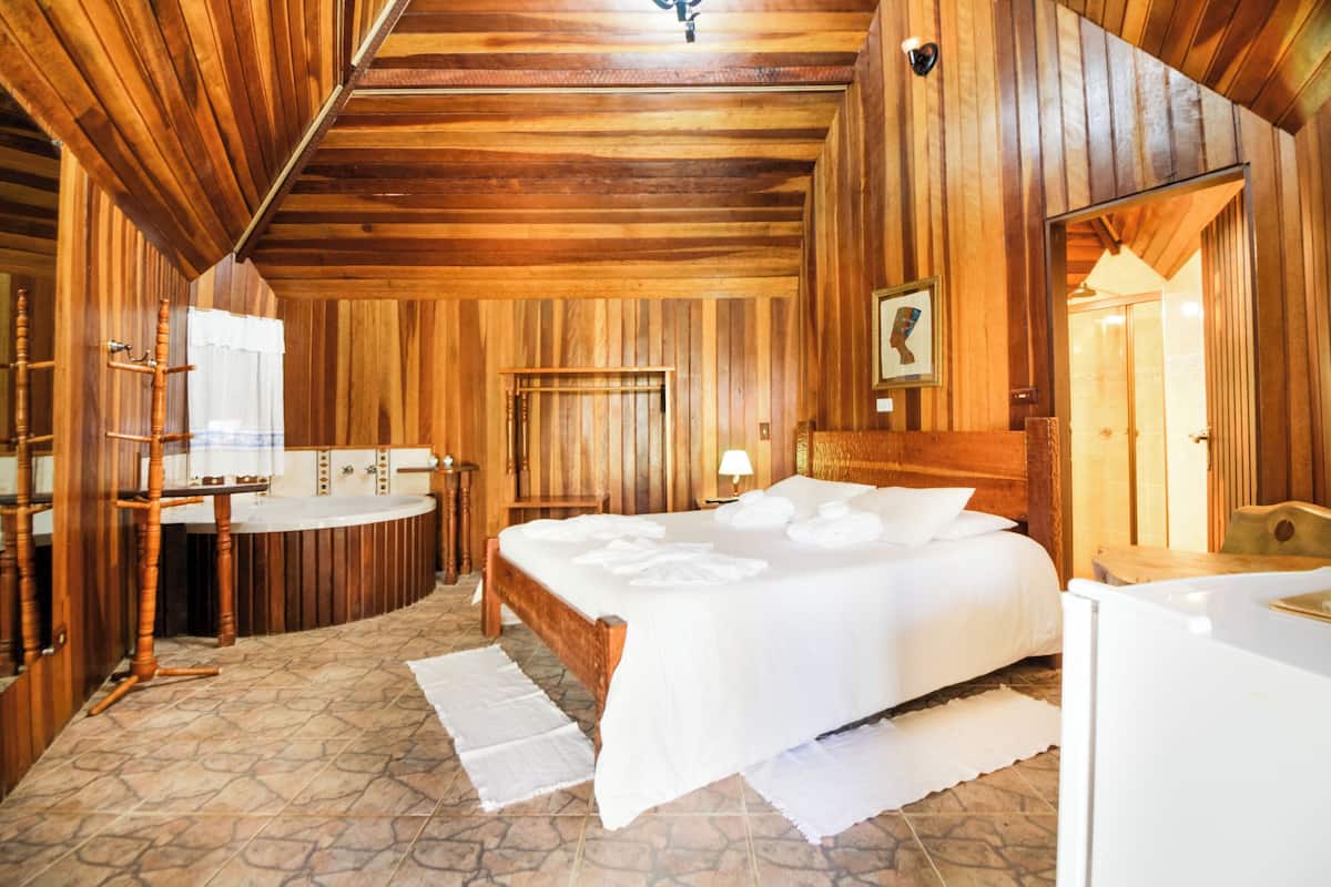 Une pièce aux finitions en bois, comprenant un lit, une coiffeuse en bois et une baignoire.