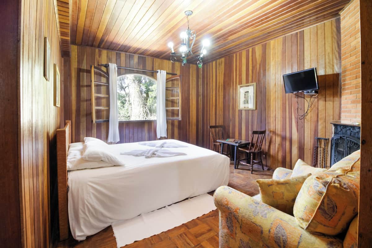 Une pièce aux murs lambrissés, comprenant un lit, un téléviseur fixé au mur, une petite table et une chaise.