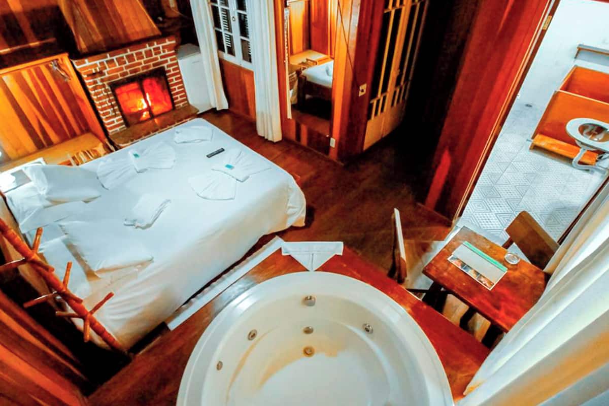 Une pièce de taille modeste comprenant un lit, une petite table, une baignoire et une cheminée.