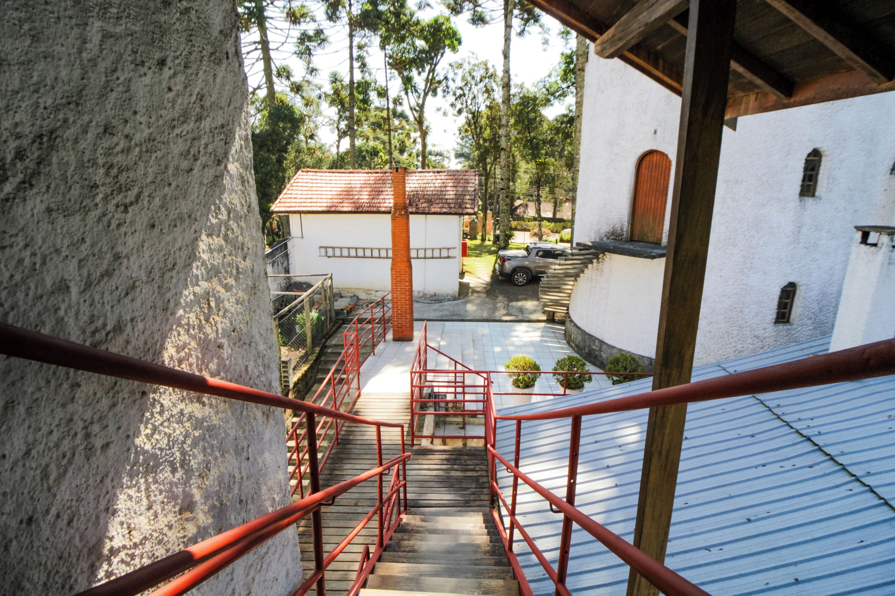 A staircase with red railings leading to a white building with a red roof.
