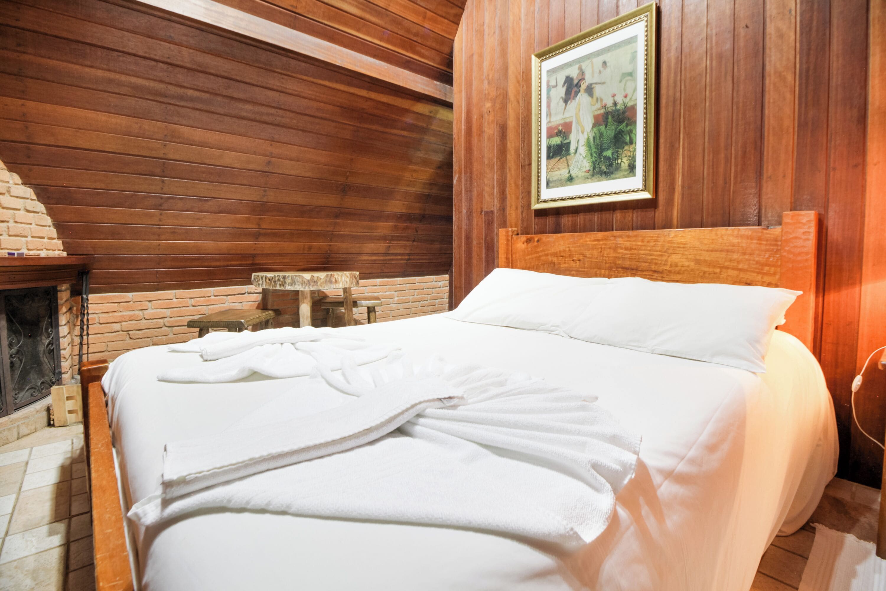 Una habitación con paneles de madera, una cama, una chimenea y un cuadro en la pared.