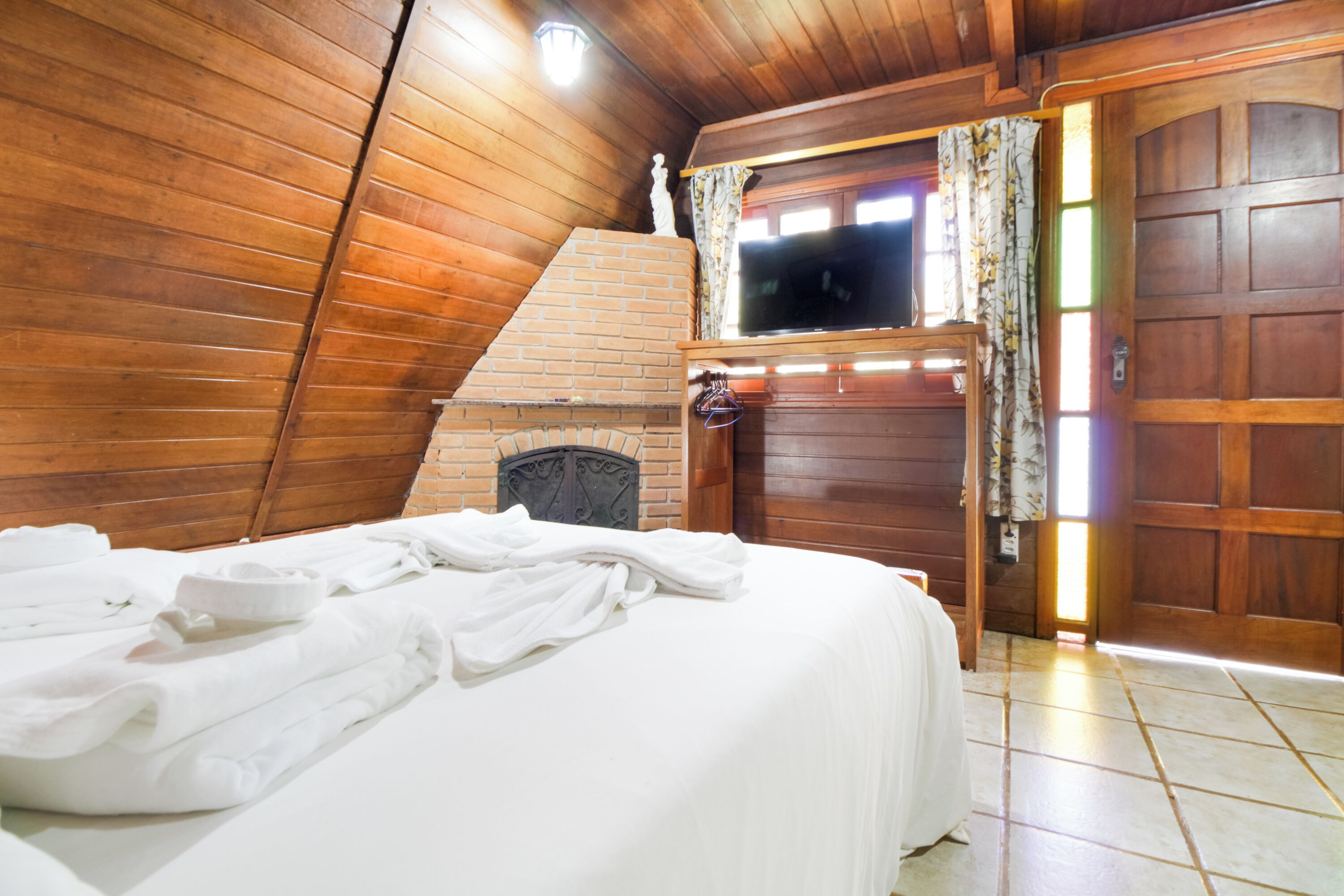 Una habitación con cama, chimenea y puerta de madera.