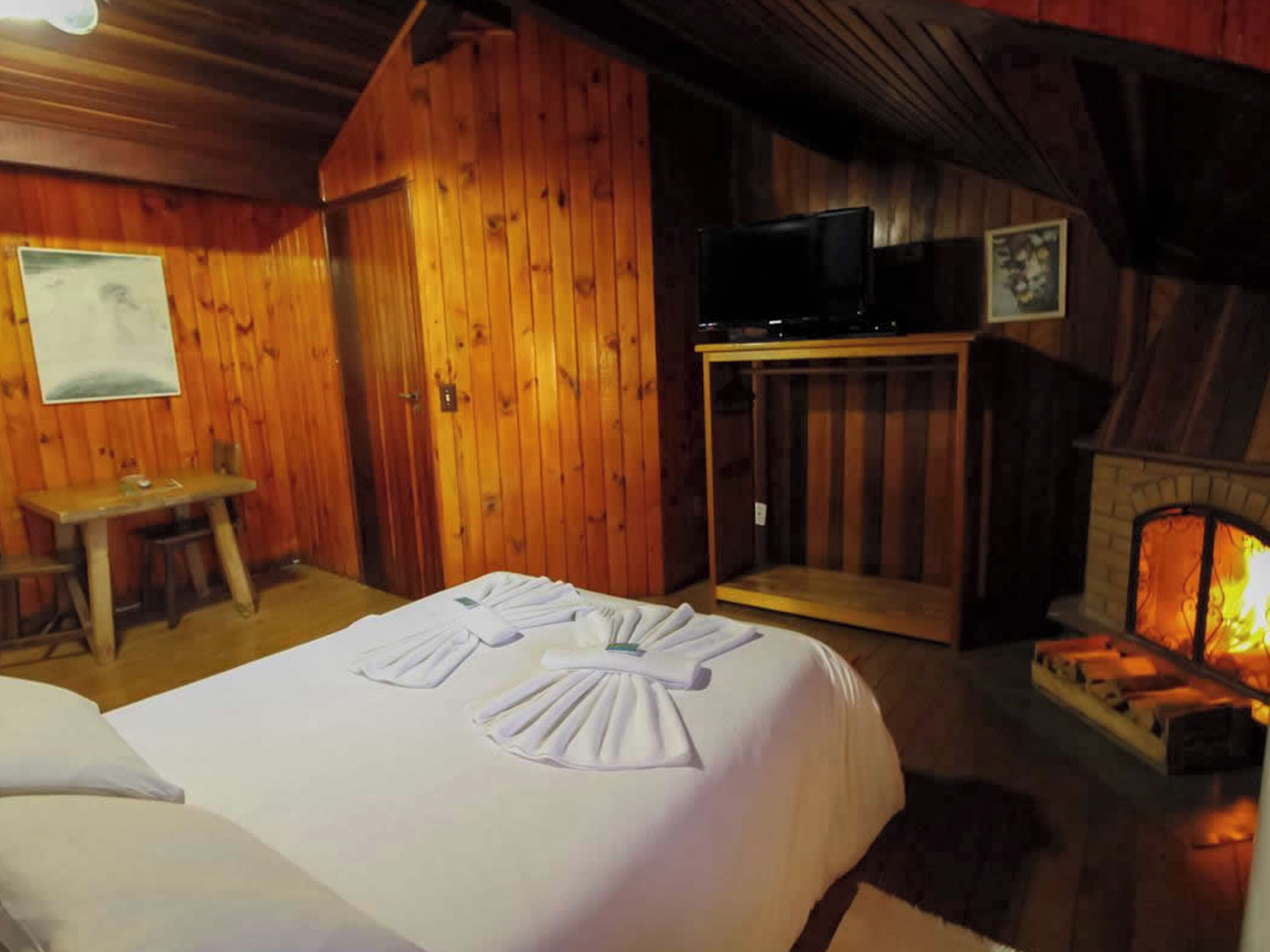 Una habitación acogedora de madera con una cama, una mesa y una chimenea.