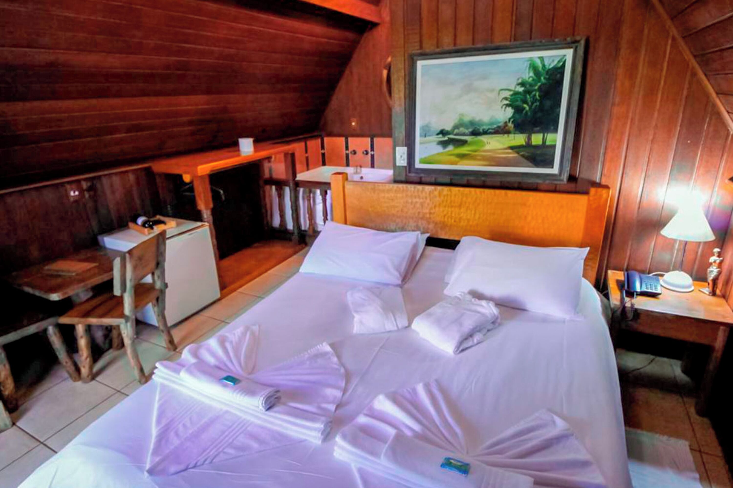 Ein holzgetäfeltes Zimmer im Chalet-Stil mit einem Bett, einem Schreibtisch und einem Bild an der Wand.