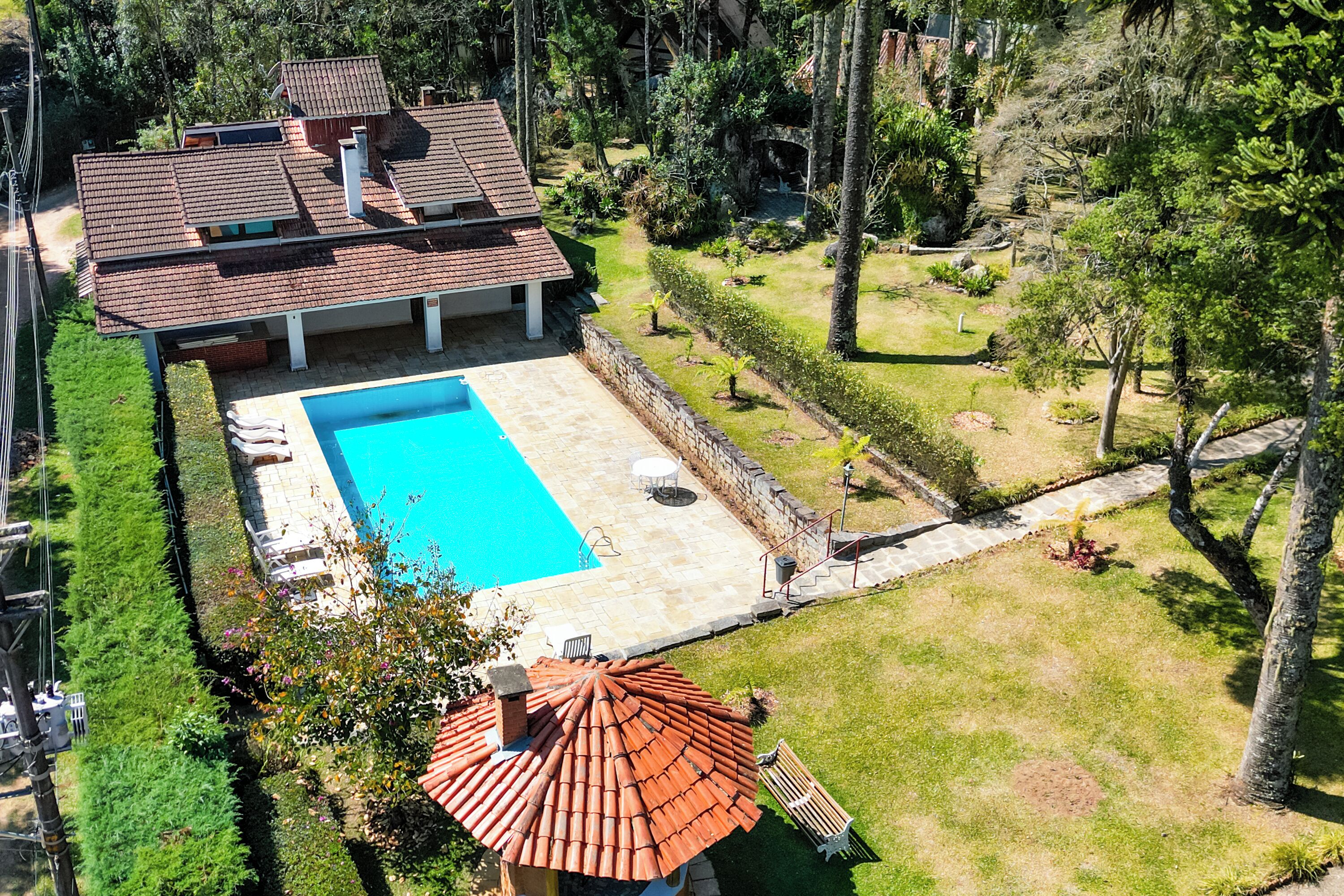 A residential property with a swimming pool, a covered patio, and a well-maintained garden.