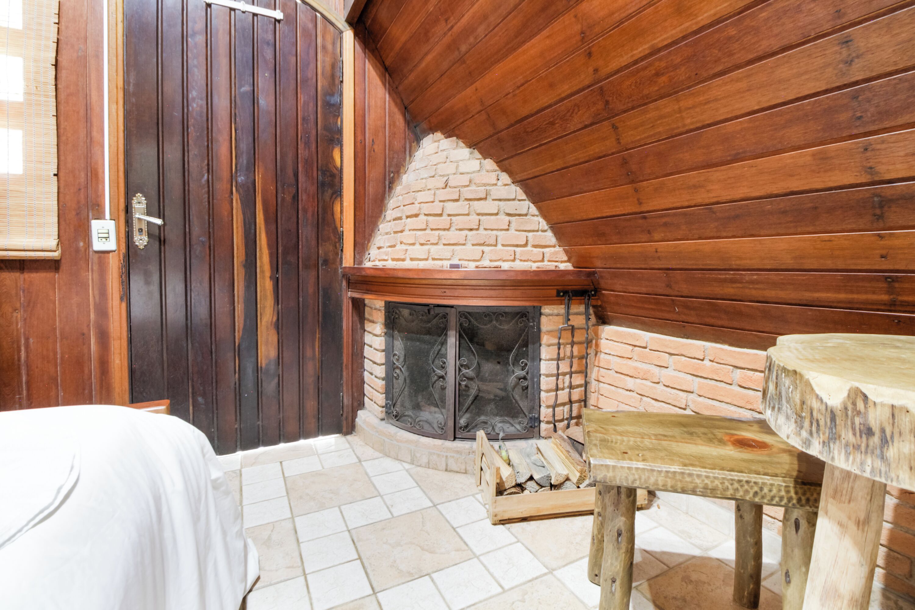 Un cuarto acogedor con puerta de madera, chimenea, cama y una pequeña mesa de madera.