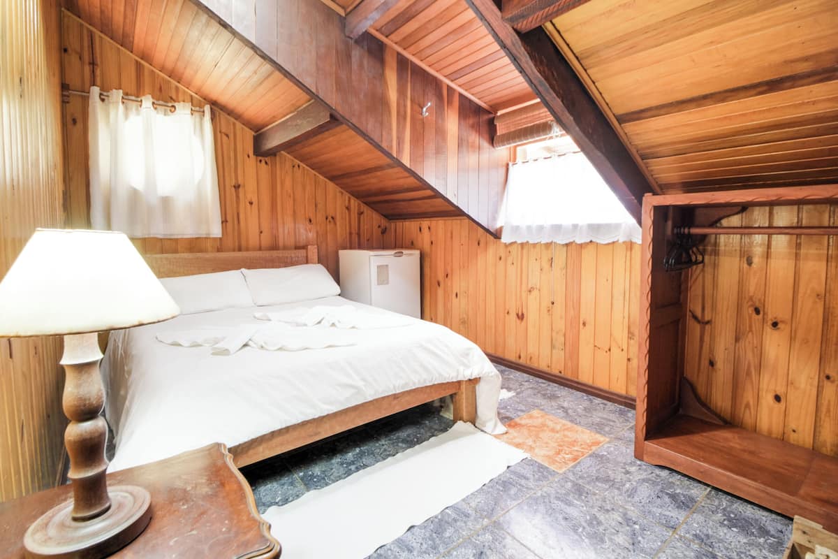 Une pièce en bois avec un lit, une lampe et un petit radiateur.