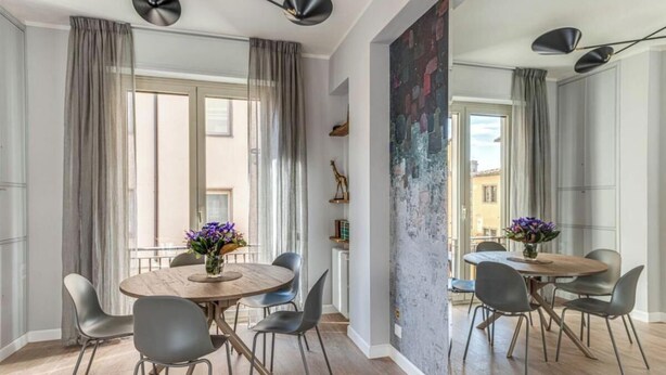 A dining area with a round table, grey chairs, and a vase of flowers. - Stunning Apartment with Ponte Vecchio and Arno River Views
 (Firenze)